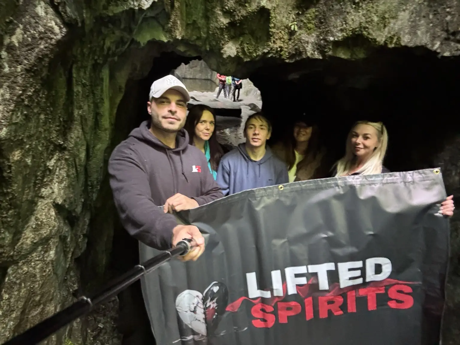 Lifted Spirits members with a community banner inside Cathedral Cave