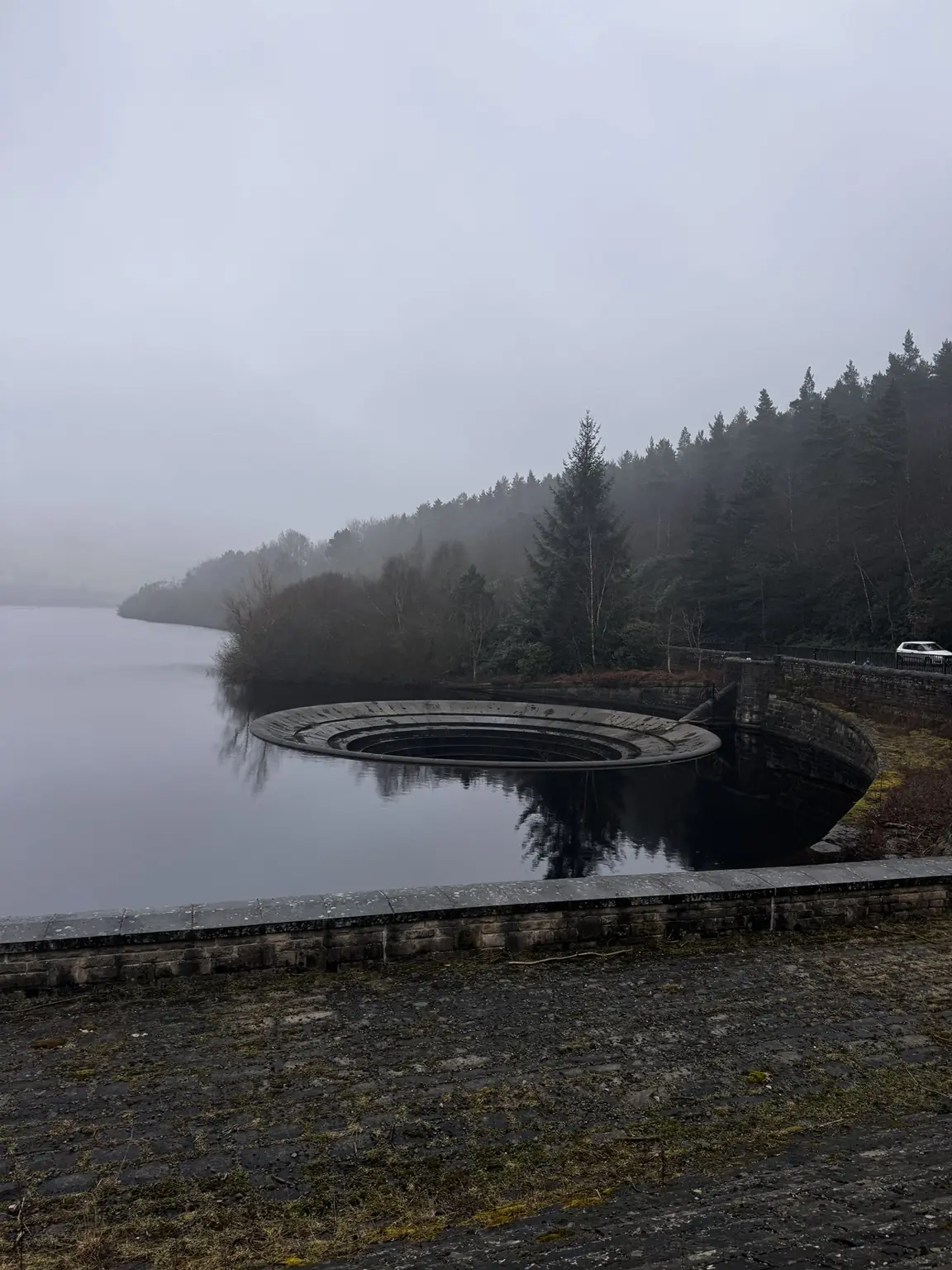 Wide view of a Ladybower Reservoir overflow in mist